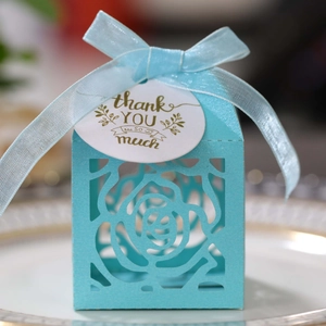 Blue hollow rose candy box with ribbon and gold-stamped thank you tag on a plate