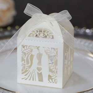 Detail of ivory laser-cut wedding candy box with heart motifs and silk ribbon
