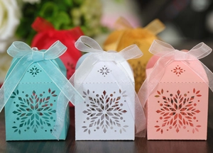 Detail of laser-cut snowflake paper candy boxes with organza ribbons in various colors