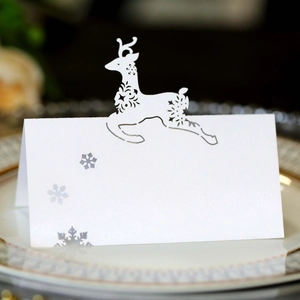 Close-up of laser-cut reindeer and snowflake white pearlescent paper wedding place cards