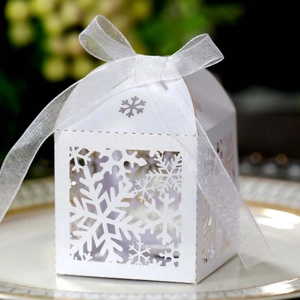 Macro shot of white laser-cut snowflake gift box with ribbon for Christmas or wedding candy
