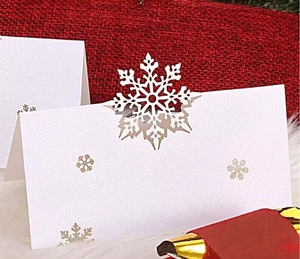White laser-cut snowflake place cards for Christmas table setting on red background