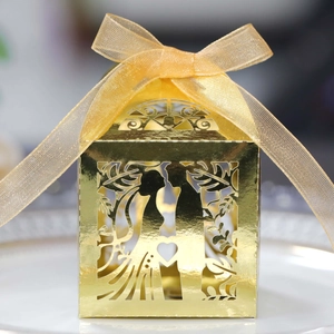 Macro detail of laser-cut gold wedding candy box with couple silhouette and organza ribbon