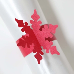 Macro di un portatovagliolo rosso a fiocco di neve su uno sfondo di raso bianco