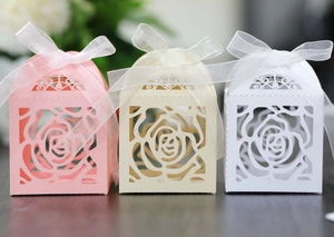 Close-up of hollow rose pattern candy boxes with satin ribbons on wood surface