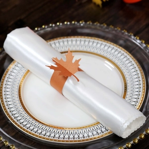 Detail of autumn maple leaf napkin ring made of laser-cut paper on a white satin cloth