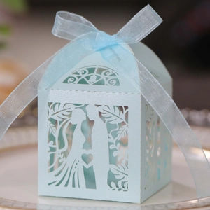 Detail of light blue laser-cut wedding favor box with ribbon and bride groom silhouette