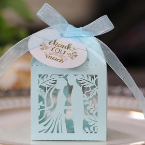 Detail of laser-cut wedding favor box in light blue with bride and groom silhouette