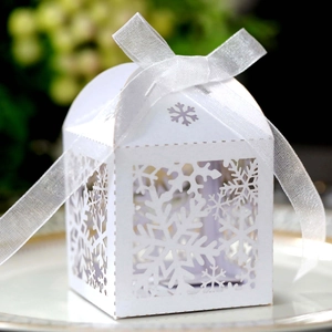 Close-up of white laser-cut Christmas candy box with snowflake patterns and ribbon