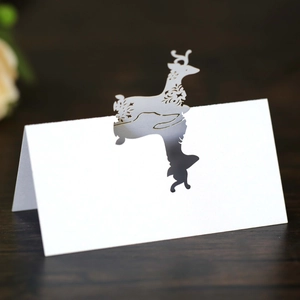 Laser-cut white reindeer place cards with hollow floral patterns on wooden table