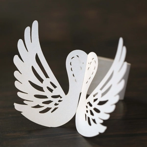 Detailed laser-cut white swan napkin ring with elegant pearlescent glitter paper texture