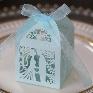 Detail of laser-cut light blue candy box with bride and groom silhouette and ribbon