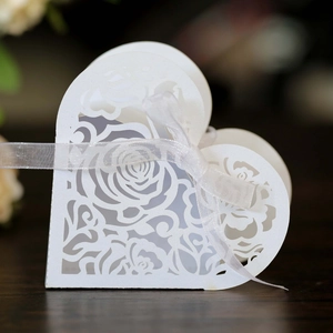 Detailed laser-cut rose pattern on white heart-shaped wedding favor box with ribbon