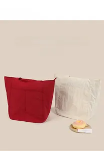 Dettaglio della borsa tote in tela rossa e crema con tasche frontali e trama del tessuto