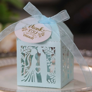 Detail of light blue laser-cut wedding favor box with ribbon and thank you tag