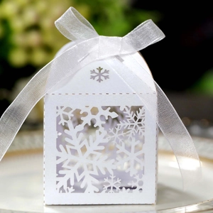 Detail of white house-shaped hollow snowflake gift box with an elegant silk ribbon bow