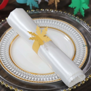 Dettaglio dell'elegante portatovagliolo a fiocco di neve dorato su tessuto bianco