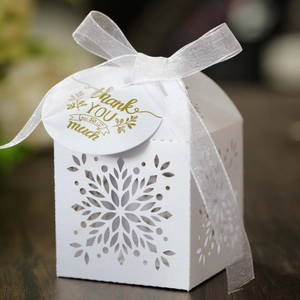 Detail view of white snowflake laser-cut candy box with organza ribbon and gift tag