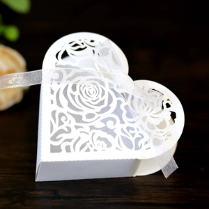 Detail of laser-cut rose patterns on a heart-shaped white paper gift box with a ribbon