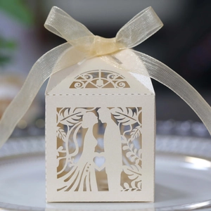 Detail of laser-cut heart and couple design on white wedding favor gift box with ribbon