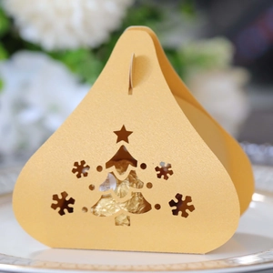 Detail of laser-cut Christmas tree and snowflake patterns on golden paper candy box