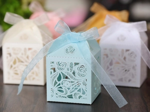 Detail of laser-cut rose patterns on light blue wedding candy box with organza ribbon