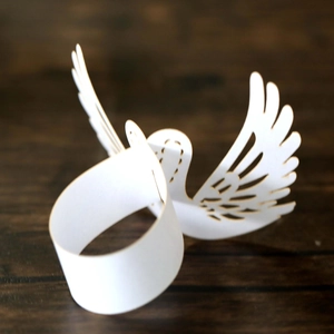 Macro shot of white laser-cut swan napkin ring with intricate hollowed patterns