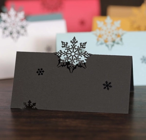 Macro detail of laser-cut black snowflake place card with multiple color variants behind