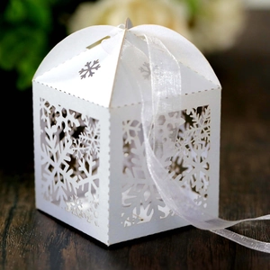 Detail of white laser-cut snowflake candy box with elegant white organza ribbon bow