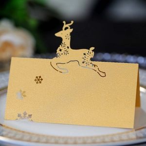 Macro shot of laser-cut reindeer and snowflake on a golden pearlescent place card
