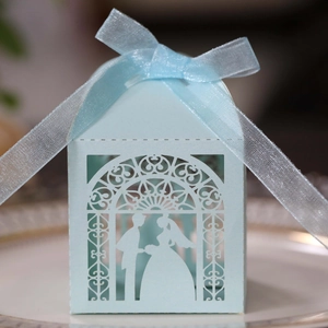 Detail of light blue hollow laser-cut wedding candy box with ribbon and bride silhouette