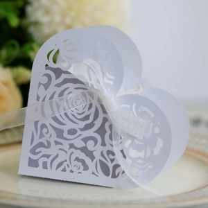 Detailed close-up of laser-cut white heart gift box with elegant ribbon on ceramic plate