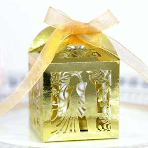 Detail of laser-cut gold wedding favor box with bride and groom silhouette and ribbon
