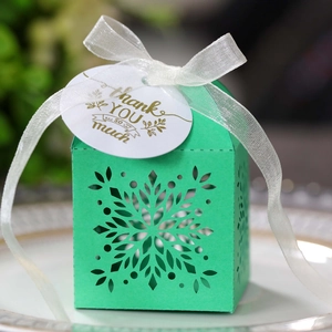 Detail of laser-cut snowflake mint green gift box with white ribbon and thank you tag
