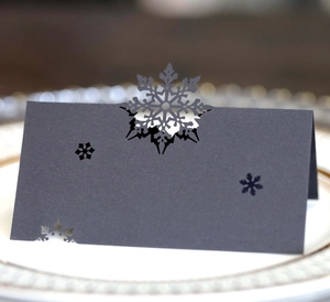Detailed laser-cut snowflake place card in black on a white porcelain dinner plate