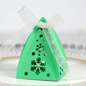 Detail van groene kerst-snoepdoos met uitgesneden sneeuwvlokken en wit satijnen lint