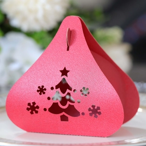 Detail of red laser-cut Christmas tree and snowflake patterns on pearlescent gift box