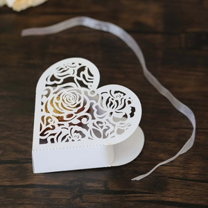 Close-up of white laser-cut heart candy box with rose pattern and gold chocolate