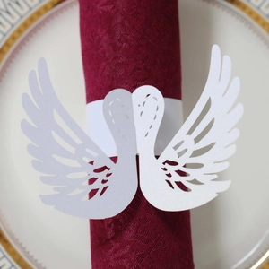 Detail of white laser-cut swan napkin ring with glitter finish on burgundy textile