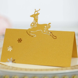 Detail of laser-cut reindeer and snowflake on a golden pearlescent paper place card