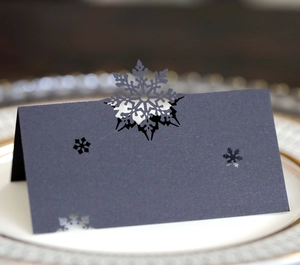 Close-up of laser-cut snowflake place card in dark grey paper on an elegant plate