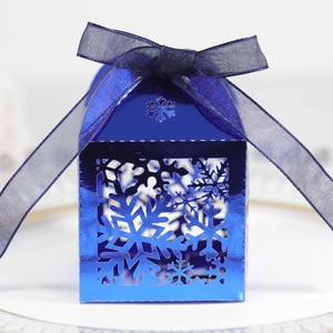 Boîte cadeau bleue avec motifs de flocons découpés au laser et ruban en soie assorti
