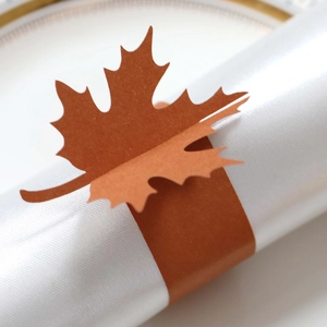 Macro view of laser-cut maple leaf napkin ring with shimmering orange pearl finish