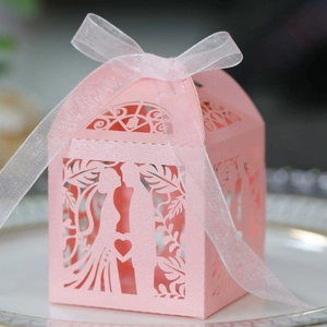 Detail of pink laser-cut wedding favor box with bride groom silhouette and organza ribbon