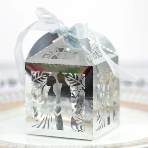Macro shot of silver mirror laser-cut wedding favor box with blue ribbon and silhouettes