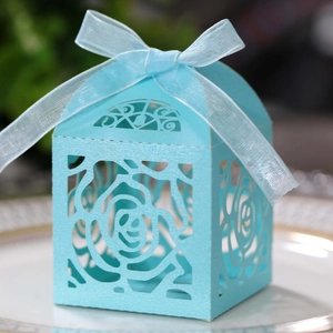 Sky blue laser-cut rose candy gift box with elegant organza ribbon on a white plate