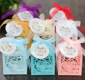 Detail of laser-cut rose hollow candy boxes with silk ribbons and thank you tags