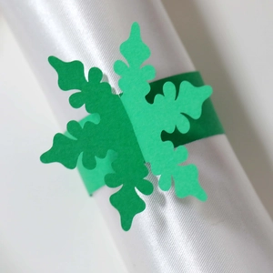 Dettaglio dell'anello portatovagliolo a forma di fiocco di neve in carta verde tagliata laser