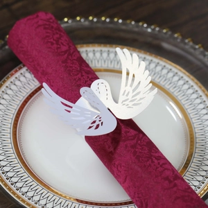 Laser-cut white swan paper napkin ring with intricate feather texture on a dinner plate