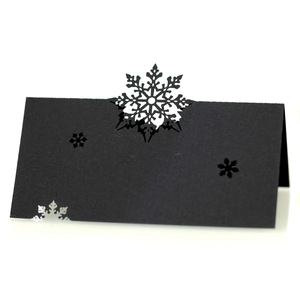 Macro view of black laser-cut snowflake place card with elegant hollowed-out patterns